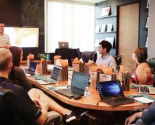 man standing in front of people sitting beside table with laptop computers